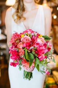 A bridal bouquet in hot pink and coral, with dahlias, sweet peas, craspedia, raspberry, and garden roses, by Floressence.