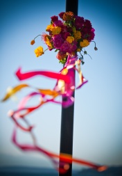 Bright pink, orange, and yellow flowers wrapped around the lamppost on the Seattle Aquarium pier, with multi-colored ribbon streaming in the wind. Design by Floressence.