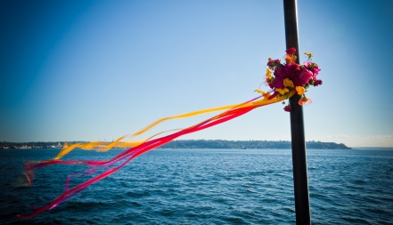 Bright pink, orange, and yellow flowers wrapped around the lamppost on the Seattle Aquarium pier, with multi-colored ribbon streaming in the wind. Design by Floressence.