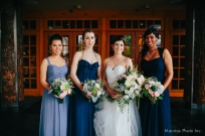 Bridesmaids in blue dresses ranging from pale to cobalt carry bouquets with blush garden roses, tweedia, silver brunia and dusty miller, astilbe, and white hydrangea. The bride carries a dramatic presentation bouquet. By Floressence.
