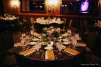 Elegant low centerpieces in silver compotes decorate the tables at an Edgewater wedding reception, by Floressence.
